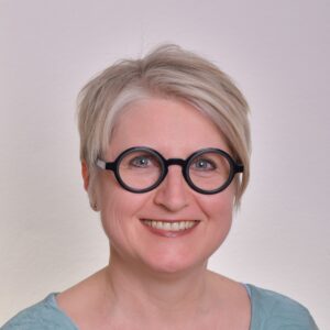 Portrait von Veronika Deuerling-Horváth - blonder Kurzhaarschnitt, runde, schwarze Brille